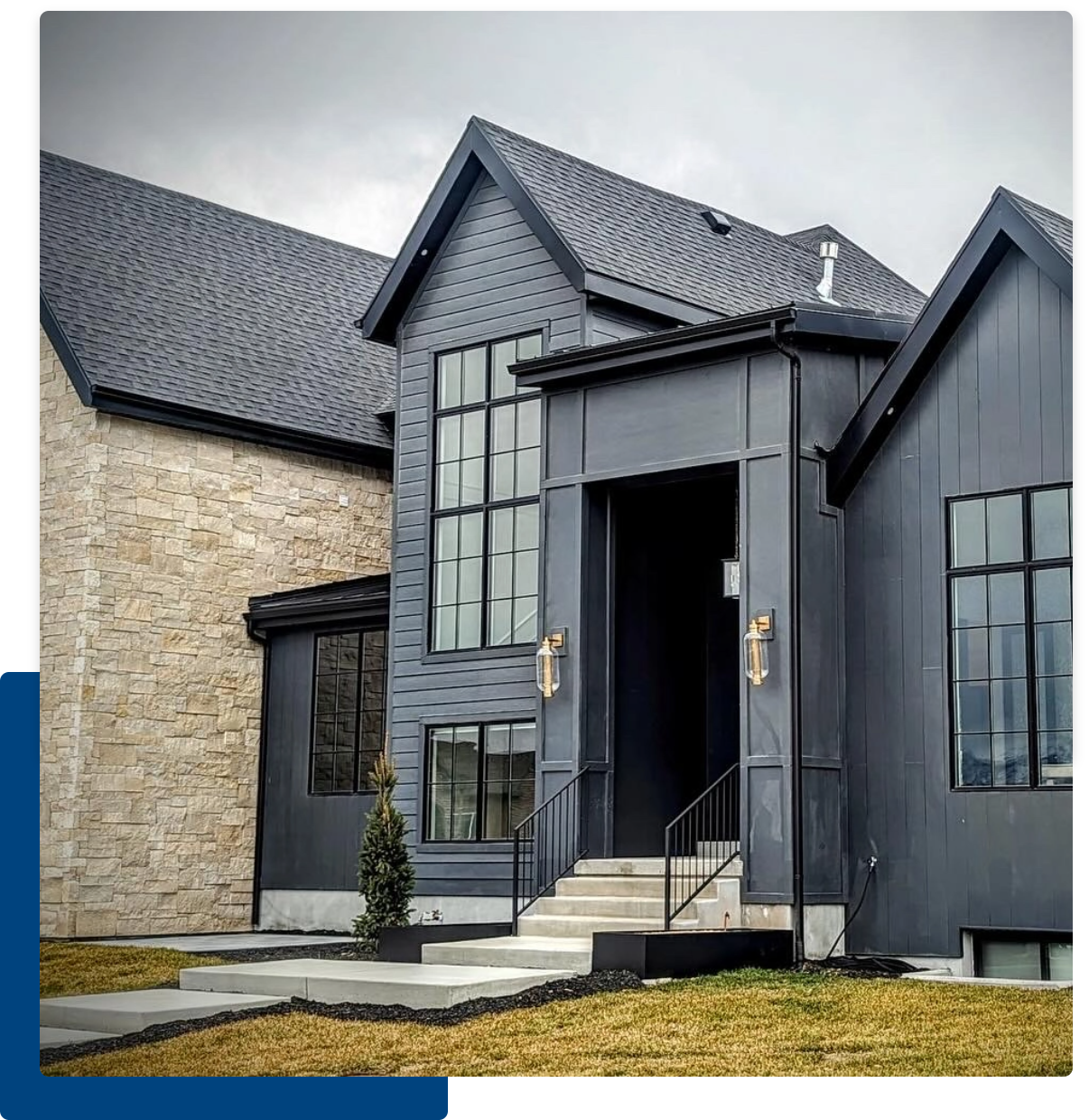 A house with blue color and stone underneath a sky with overcast