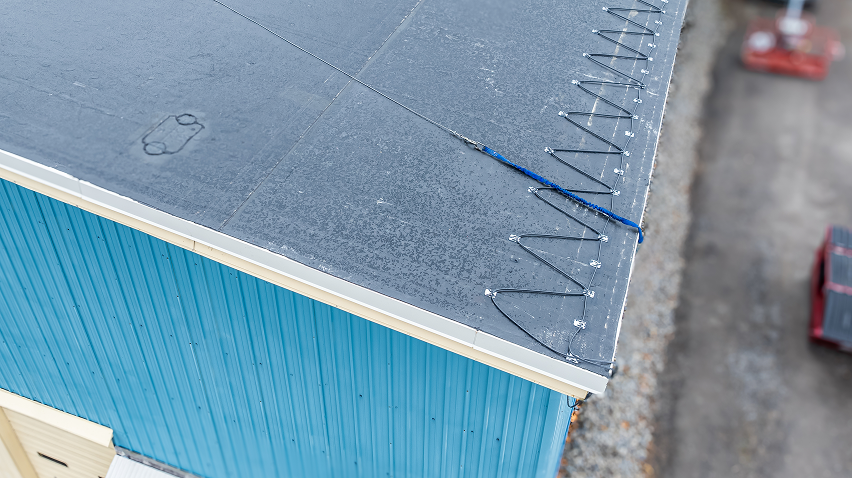 Up close view of heating cables being installed on roof with clips