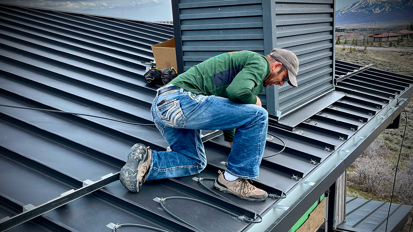 Employee or contractor working on a roof, installing heat cables